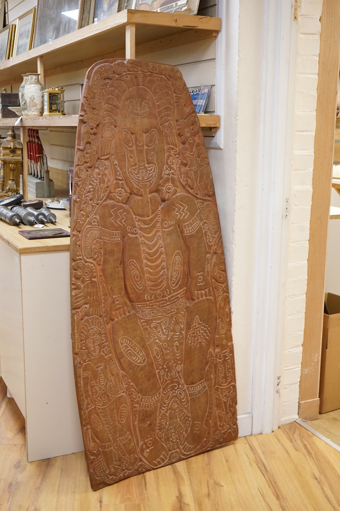 A Papua New Guinea Sepik River large wooden storyboard, relief carved and incised with a central figure surrounded by various animals and spirits, with traces of white pigment, 152cm high